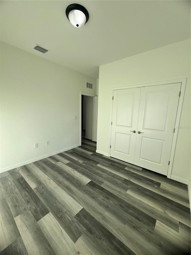 unfurnished bedroom with dark hardwood / wood-style flooring and a closet