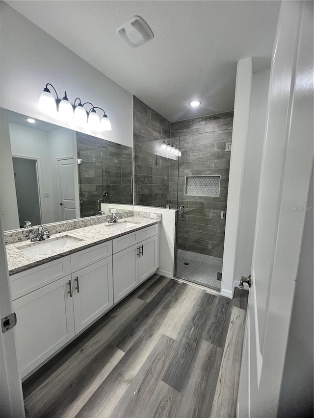 bathroom featuring hardwood / wood-style flooring, vanity, and walk in shower