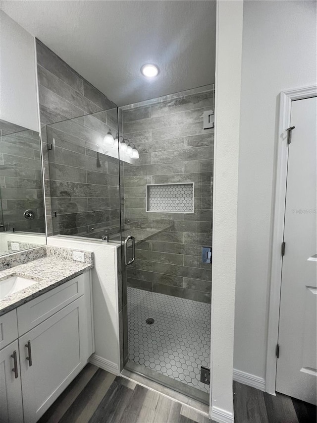 bathroom with wood-type flooring, vanity, and a shower with door