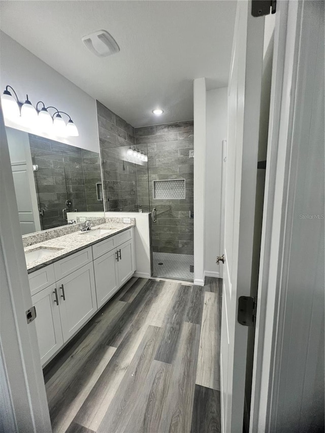 bathroom with hardwood / wood-style flooring, vanity, and walk in shower