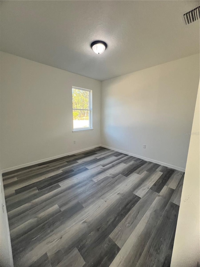 unfurnished room with dark hardwood / wood-style flooring and a textured ceiling