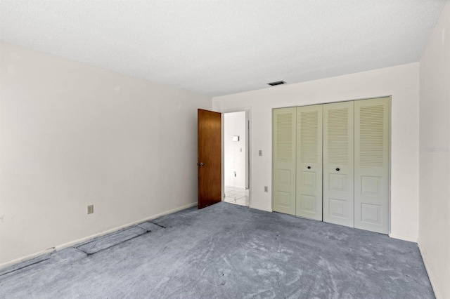 unfurnished bedroom with a closet, dark carpet, and a textured ceiling