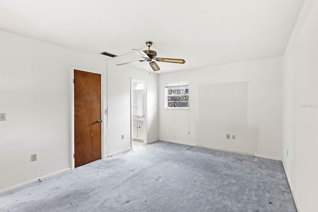 spare room featuring ceiling fan, light colored carpet, and a textured ceiling