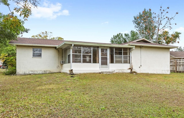 back of property with a lawn and a sunroom