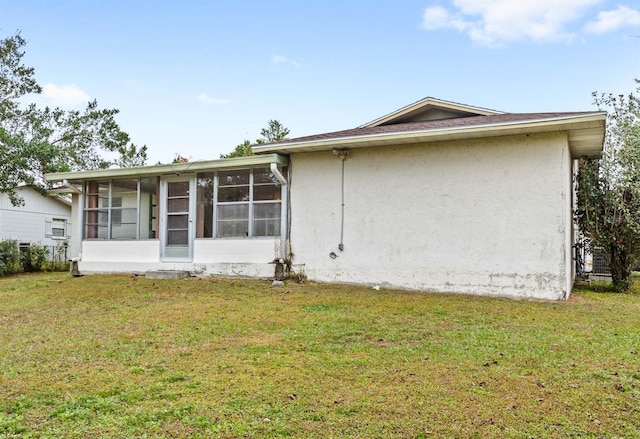 view of side of home featuring a sunroom and a yard