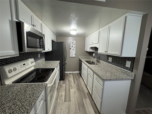 kitchen featuring white cabinets, sink, light stone countertops, appliances with stainless steel finishes, and light hardwood / wood-style floors