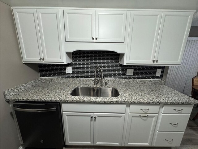 kitchen featuring white cabinets, light stone counters, sink, and black dishwasher