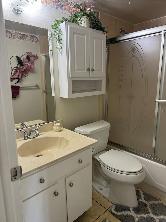 full bathroom with tile patterned floors, vanity, bath / shower combo with glass door, and toilet