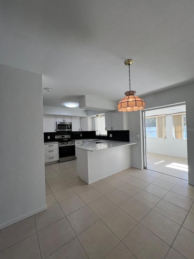 kitchen featuring white cabinetry, stainless steel appliances, kitchen peninsula, pendant lighting, and light tile patterned floors