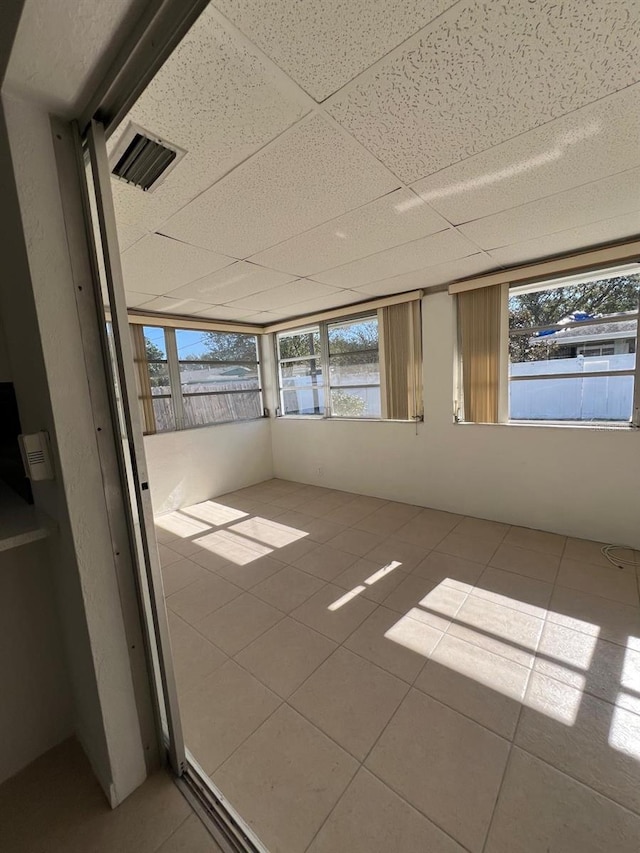 unfurnished sunroom featuring a drop ceiling