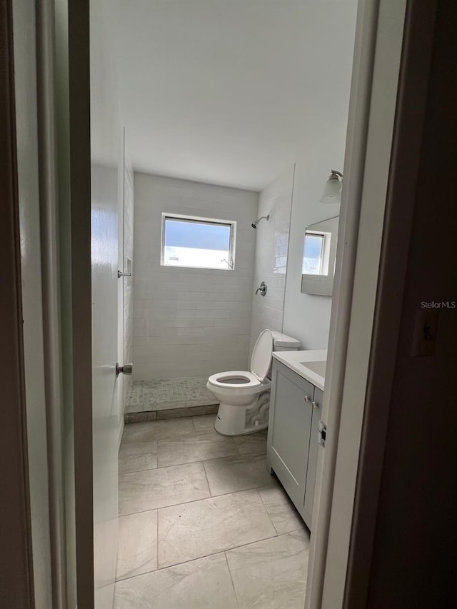 bathroom featuring vanity, toilet, and a tile shower