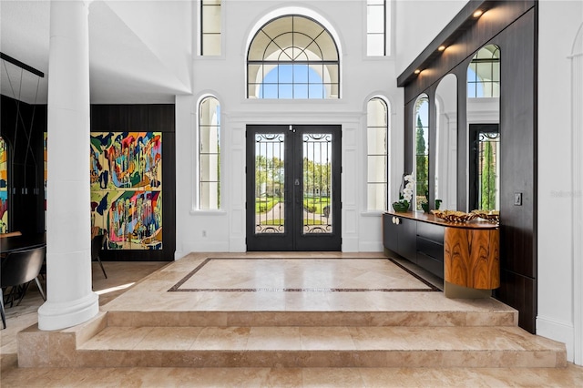 entryway with french doors, decorative columns, and a high ceiling