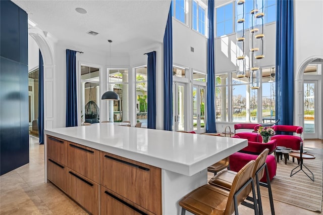 kitchen with a center island, a towering ceiling, pendant lighting, a textured ceiling, and a breakfast bar