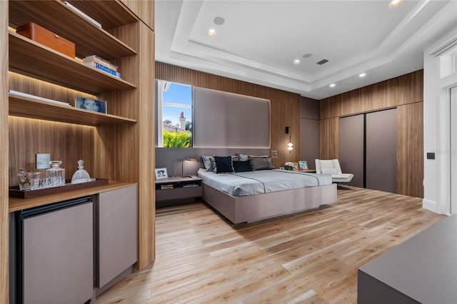 bedroom with a raised ceiling, stainless steel fridge, a closet, and light hardwood / wood-style flooring