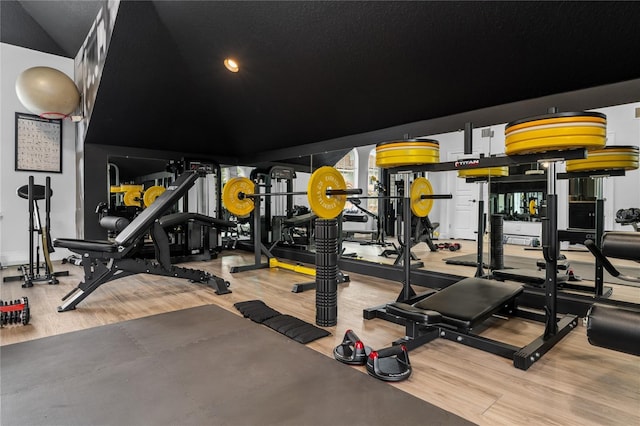 gym featuring hardwood / wood-style floors and vaulted ceiling