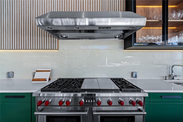 kitchen with extractor fan, tasteful backsplash, range with two ovens, and green cabinetry