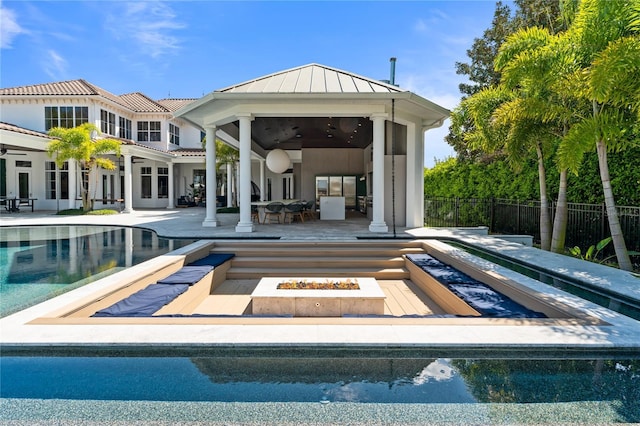 rear view of house featuring a patio, a fenced in pool, a fire pit, and ceiling fan