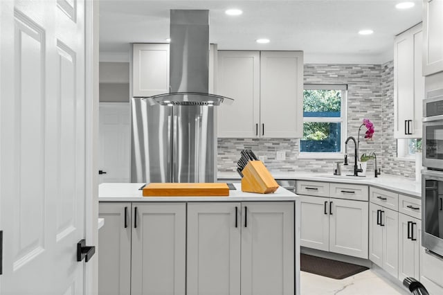 kitchen featuring island range hood, ornamental molding, sink, and tasteful backsplash