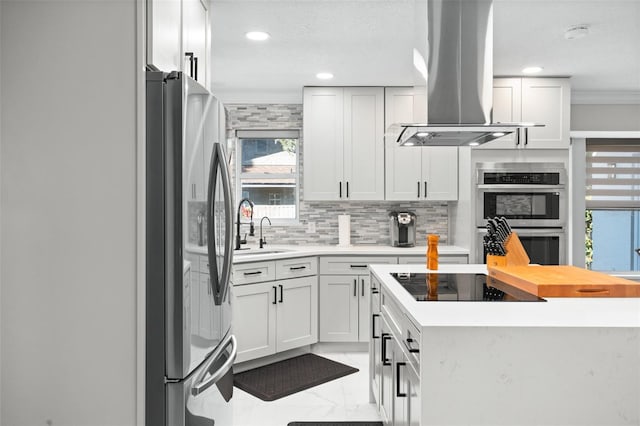 kitchen with white cabinetry, sink, tasteful backsplash, island exhaust hood, and appliances with stainless steel finishes