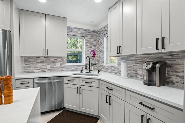 kitchen with decorative backsplash, sink, a textured ceiling, and appliances with stainless steel finishes