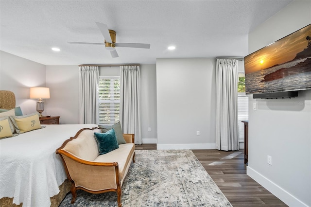 bedroom with a textured ceiling, ceiling fan, and dark wood-type flooring