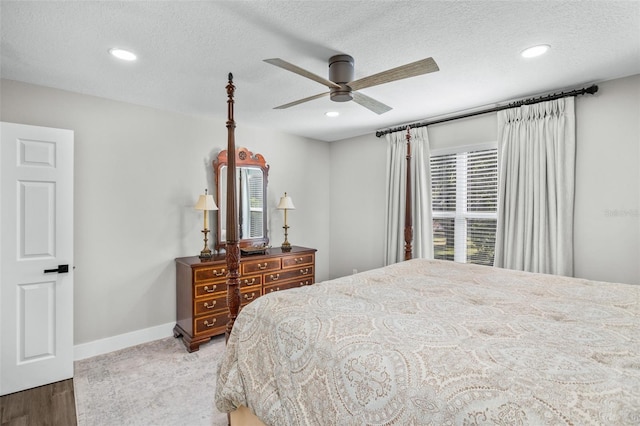 bedroom with ceiling fan, wood-type flooring, and a textured ceiling