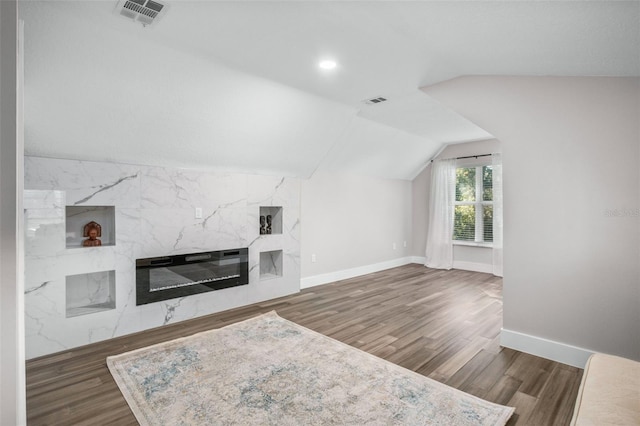 unfurnished living room with dark hardwood / wood-style flooring, a premium fireplace, and vaulted ceiling