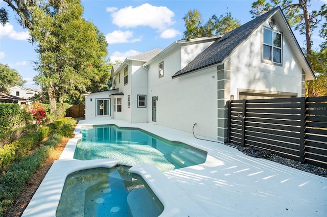 rear view of property featuring a swimming pool with hot tub