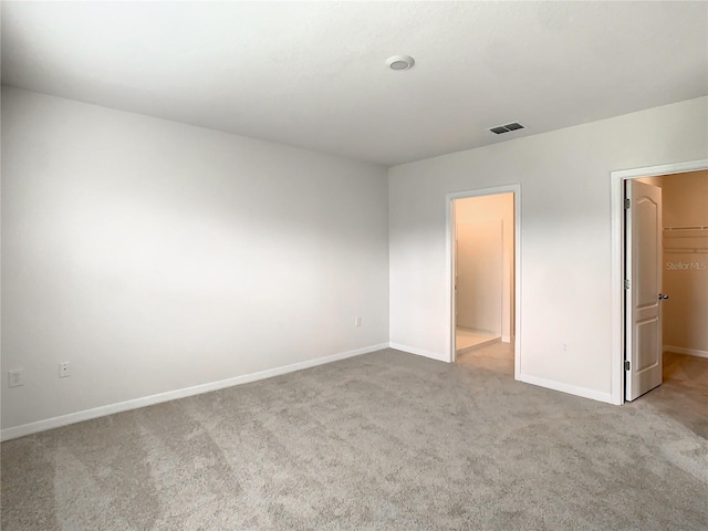 unfurnished bedroom with light colored carpet, a spacious closet, and a closet