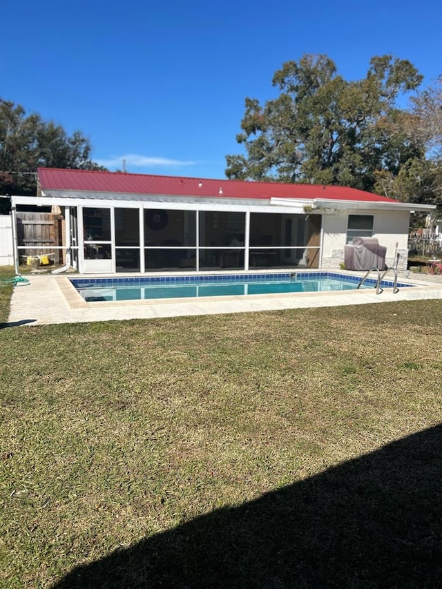 view of swimming pool with a sunroom, a patio area, and a lawn