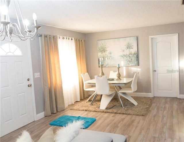 dining room featuring an inviting chandelier, a textured ceiling, and light wood-type flooring