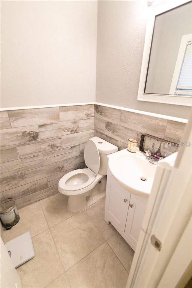 bathroom featuring tile patterned flooring, vanity, toilet, and tile walls