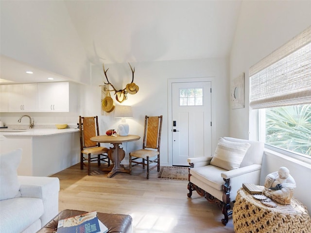 living room with light hardwood / wood-style flooring, lofted ceiling, and sink