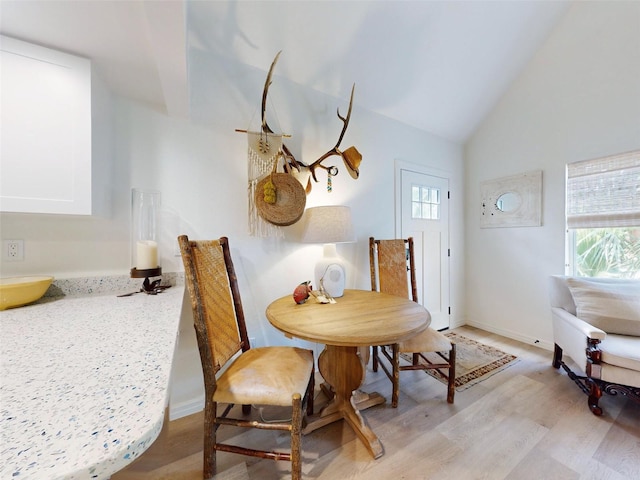 dining space featuring light hardwood / wood-style floors and lofted ceiling