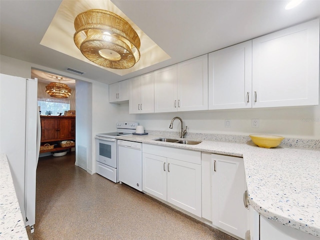 kitchen with white appliances, a raised ceiling, sink, light stone counters, and white cabinetry