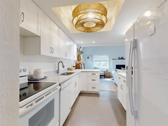 kitchen with kitchen peninsula, white appliances, a tray ceiling, and sink