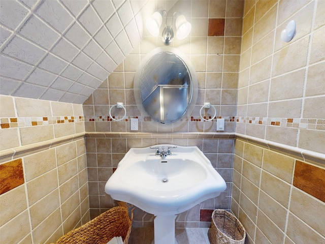 bathroom with lofted ceiling, sink, and tile walls