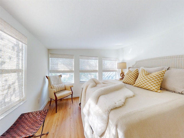 bedroom featuring wood-type flooring, vaulted ceiling, and multiple windows