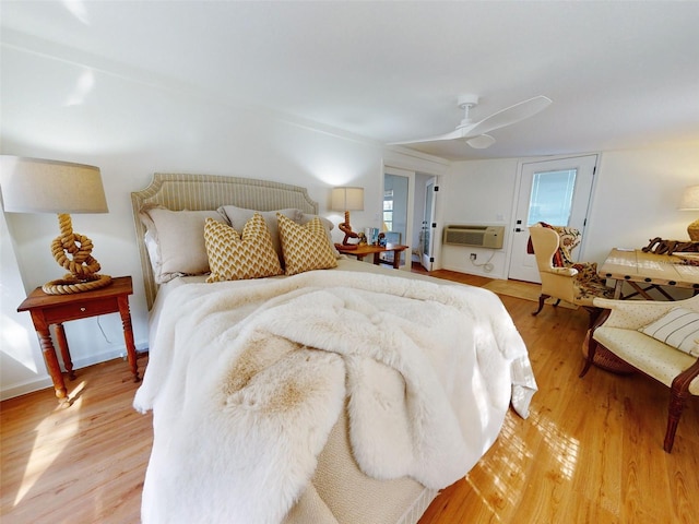 bedroom with ceiling fan, light hardwood / wood-style floors, and a wall mounted AC