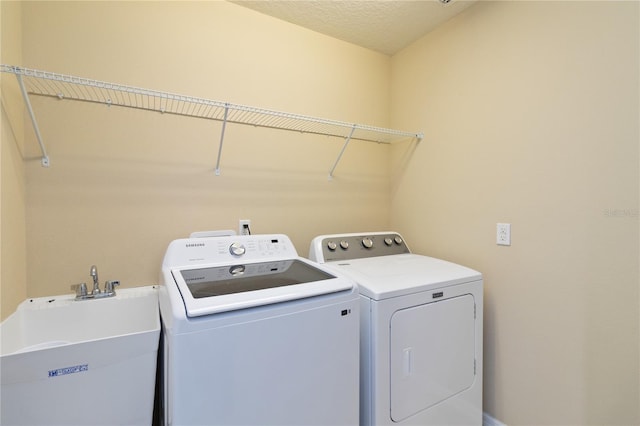 washroom featuring sink, a textured ceiling, and washing machine and dryer