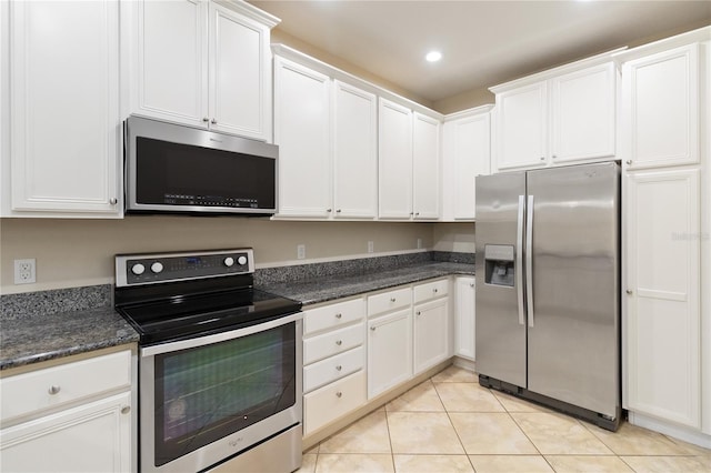 kitchen featuring white cabinets, dark stone countertops, light tile patterned floors, and appliances with stainless steel finishes