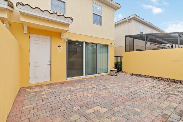 back of property with glass enclosure and a patio