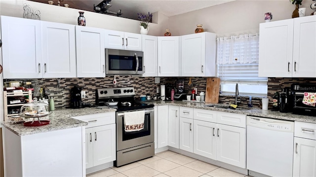 kitchen with white cabinetry, sink, light stone counters, light tile patterned floors, and appliances with stainless steel finishes