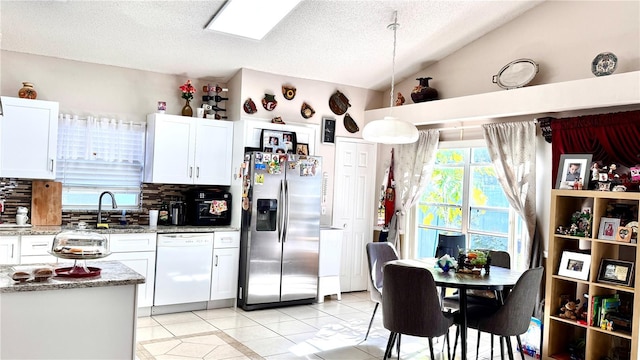 kitchen featuring dishwasher, white cabinets, vaulted ceiling, stainless steel fridge, and decorative light fixtures