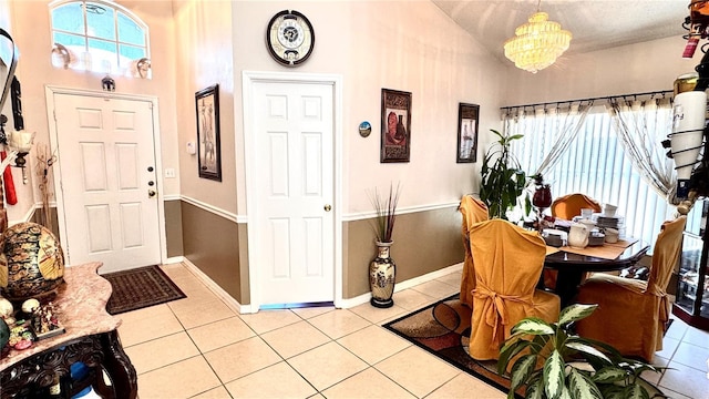 tiled foyer entrance with vaulted ceiling and an inviting chandelier