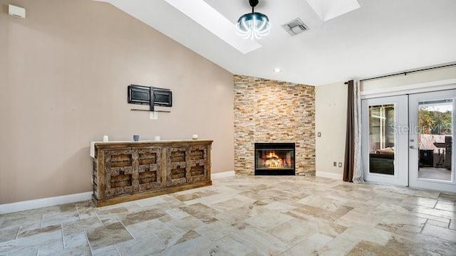 unfurnished living room with a fireplace, french doors, and lofted ceiling with skylight