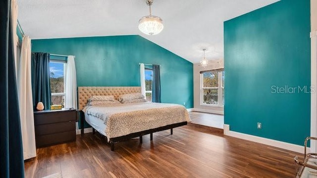 bedroom with a chandelier, hardwood / wood-style flooring, vaulted ceiling, and multiple windows