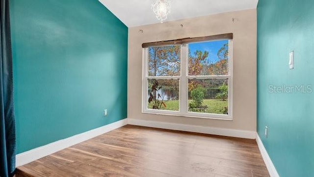 unfurnished room with hardwood / wood-style flooring and an inviting chandelier