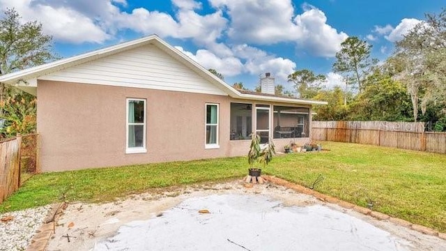 rear view of property featuring a sunroom and a yard