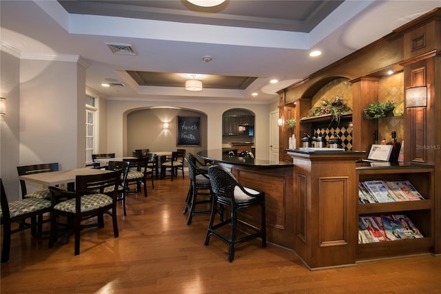 bar with dark hardwood / wood-style floors, crown molding, and a tray ceiling